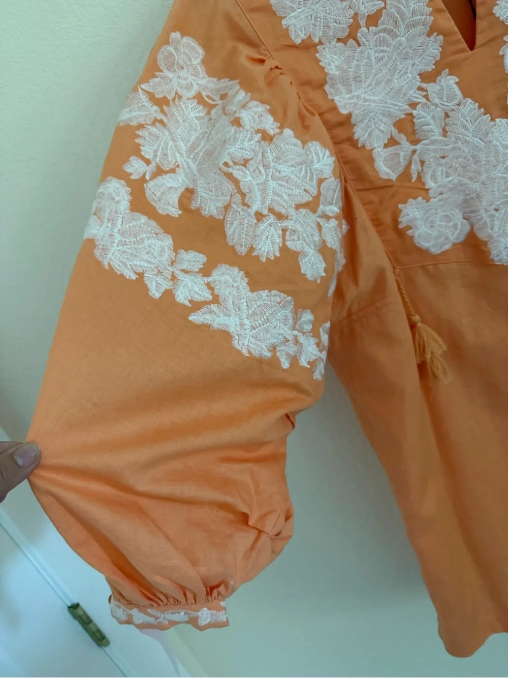 Blouse features split neckline with ties and voluminous embroidered puff sleeves